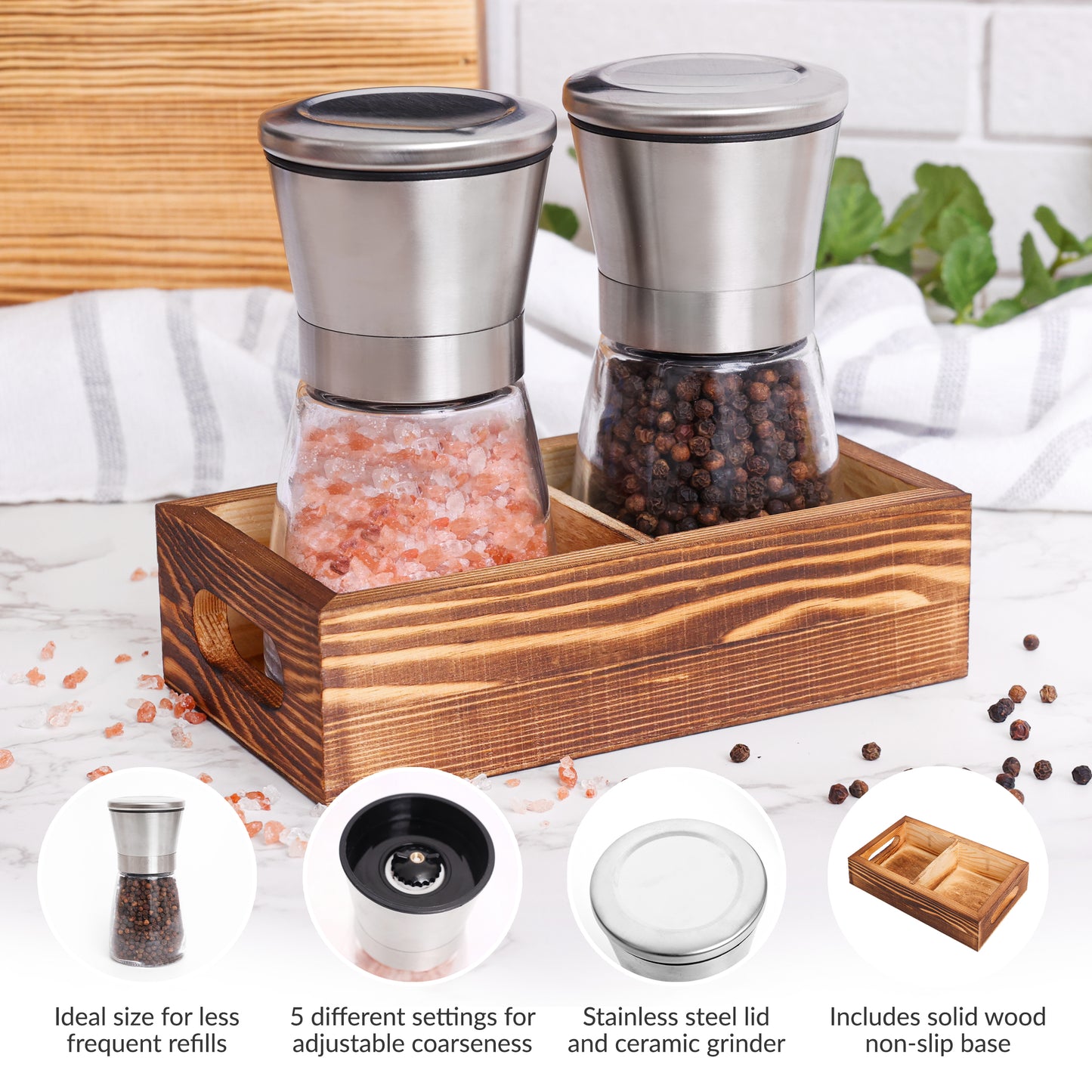 Stainless Salt and pepper grinder set with a wooden caddy on a kitchen counter.
